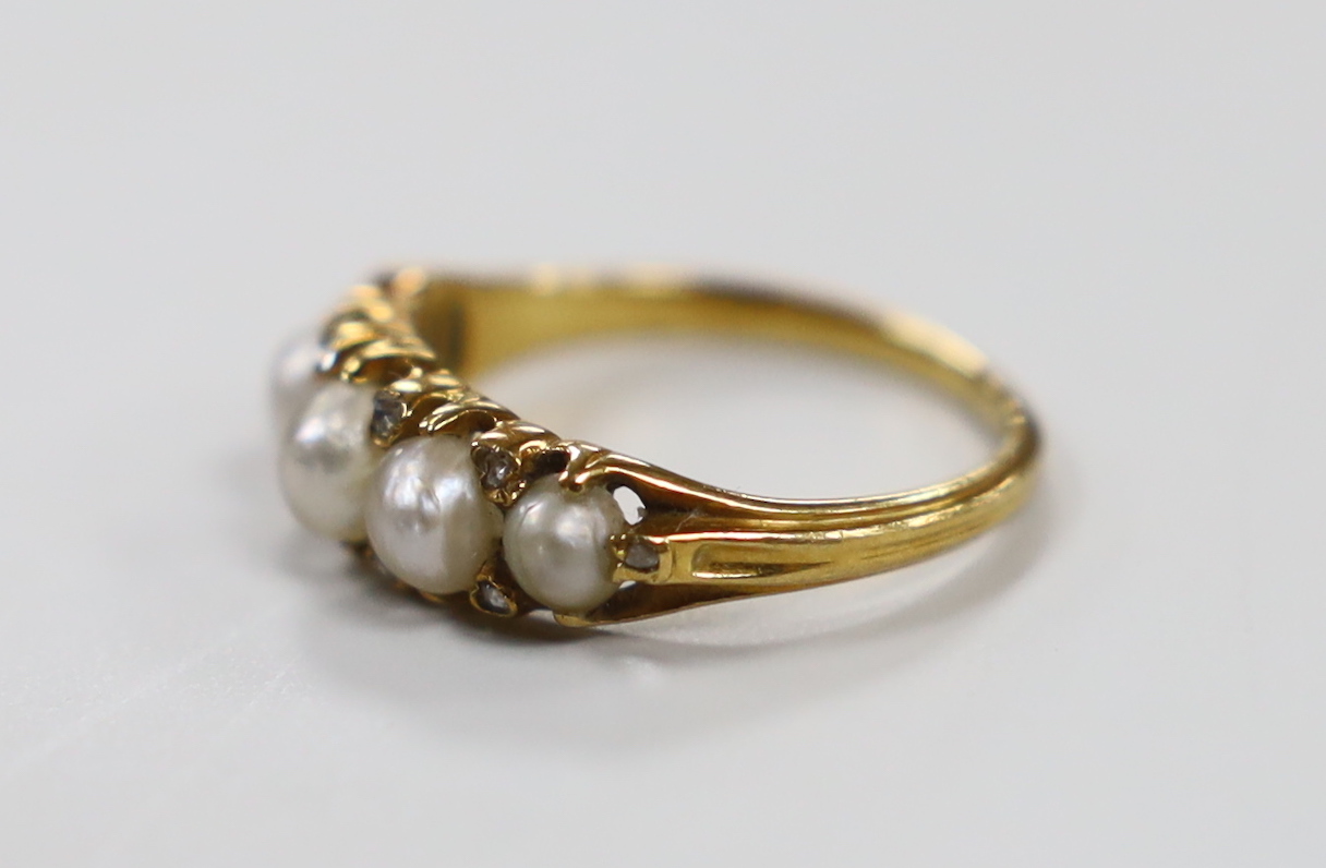 An Edwardian yellow metal and graduated split pearl set half hoop ring, with diamond chip spacers, size M, gross weight 3.1 grams.